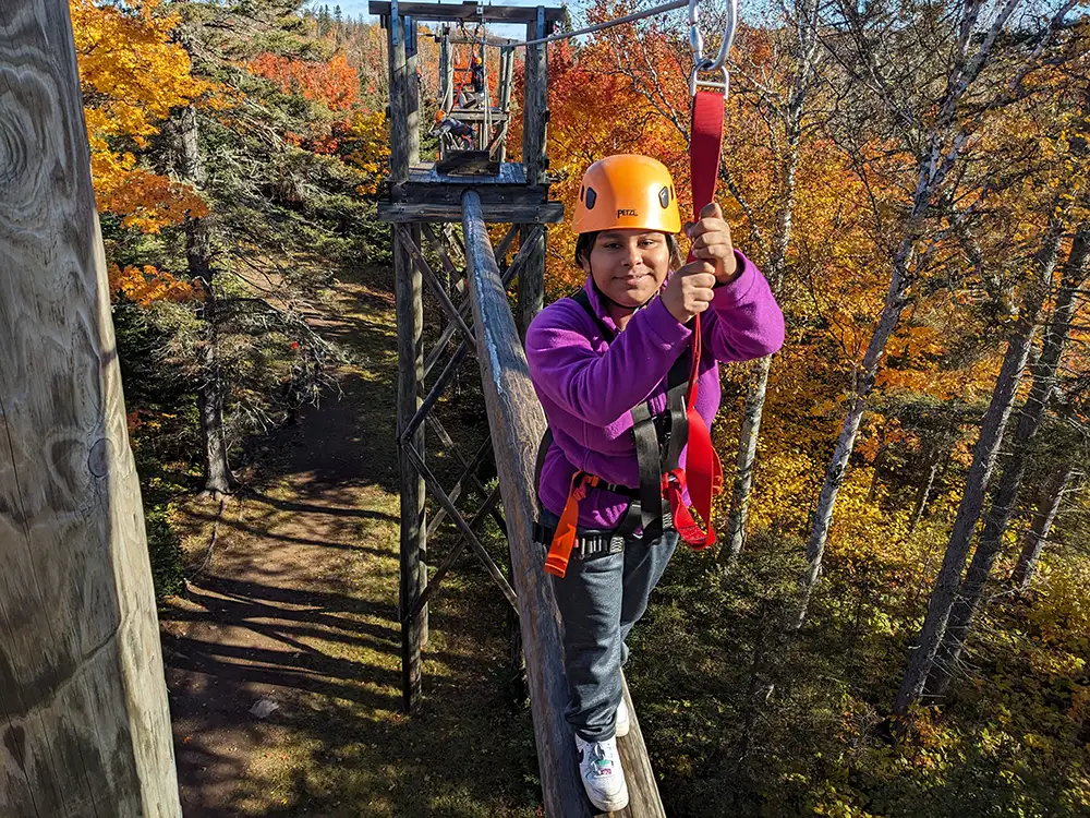 Photo of child climbing across an obstical course attached to a rope.