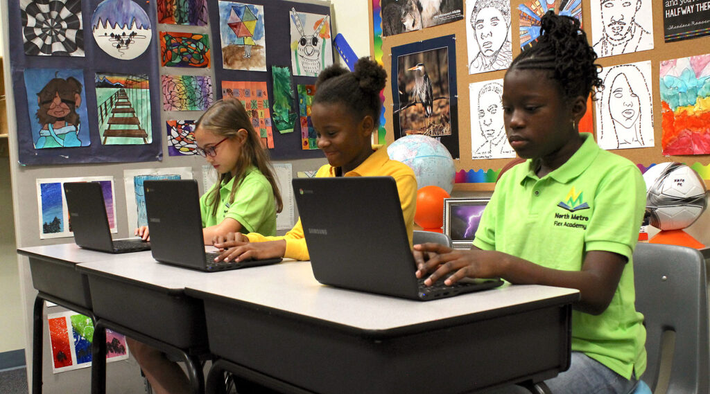 Three students doing class work on laptops