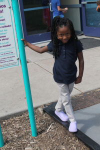 young girl standing next to sign smiling
