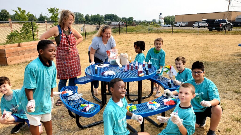 Two teachers and 8 students outside making tie-dyed shirts