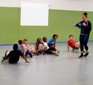 gym teacher teaching physical education with kids in crab walk positions on the floor